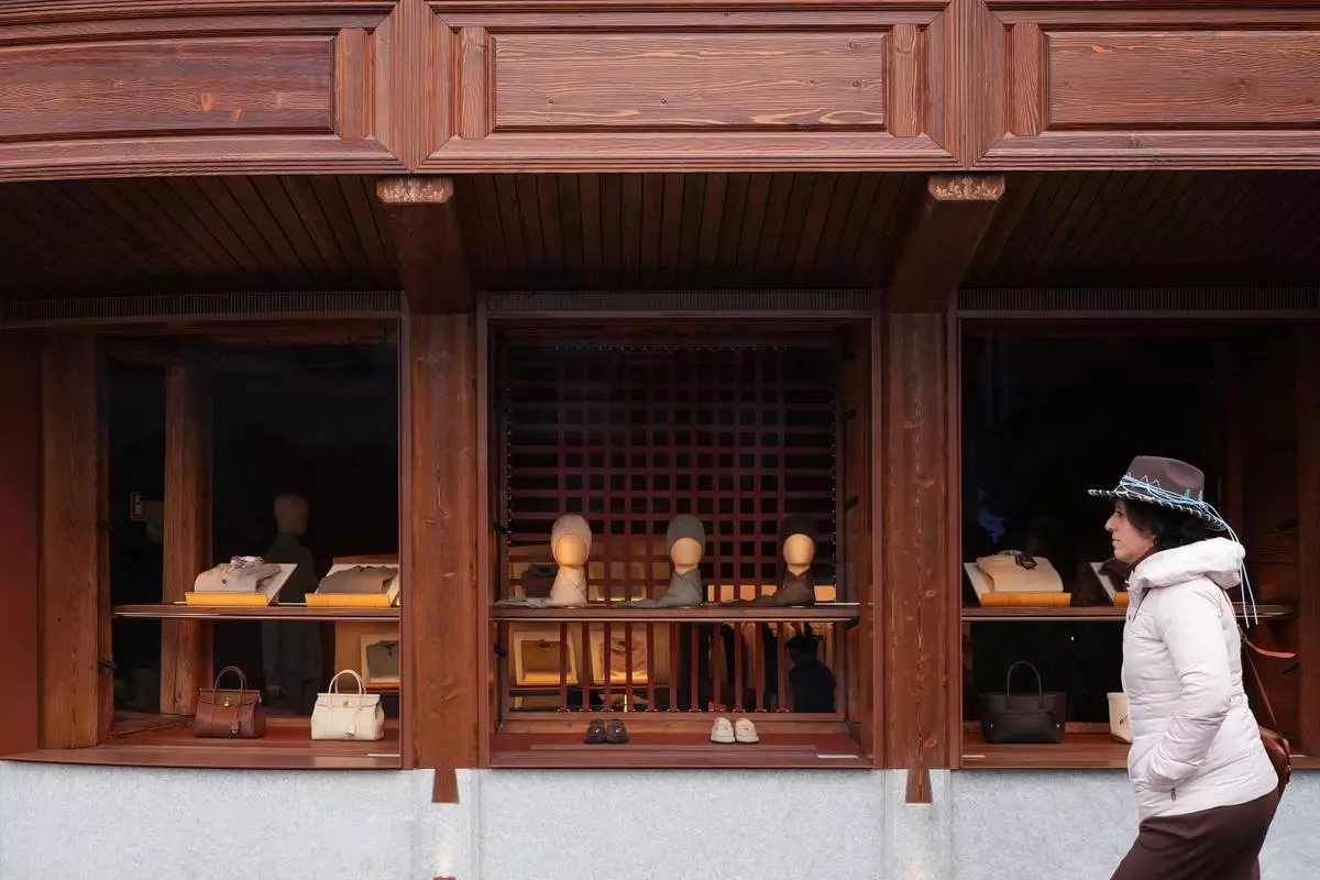 A woman walks past Loro Piana luxury shop in Cortina d'Ampezzo, Italy, Saturday, Feb. 14, 2026. (AP Photo/Alessandra Tarantino)