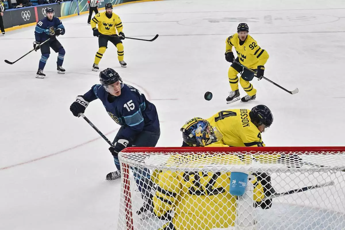 Finland's Anton Lundell, left, scores his team's second goal past Sweden's Filip Gustavsson, during a preliminary round match of men's ice hockey between Finland and Sweden at the 2026 Winter Olympics, in Milan, Italy, Friday, Feb. 13, 2026. (Alexander Nemenov/Pool Photo via AP)