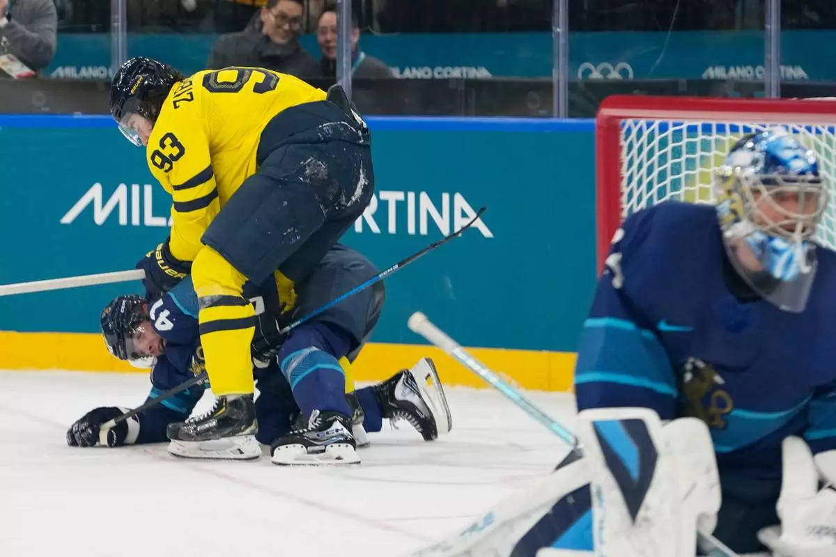 Sweden's Mika Zibanejad, up, challenges Finland's Miro Heiskanen during a preliminary round match of men's ice hockey between Finland and Sweden at the 2026 Winter Olympics, in Milan, Italy, Friday, Feb. 13, 2026. (AP Photo/Hassan Ammar)