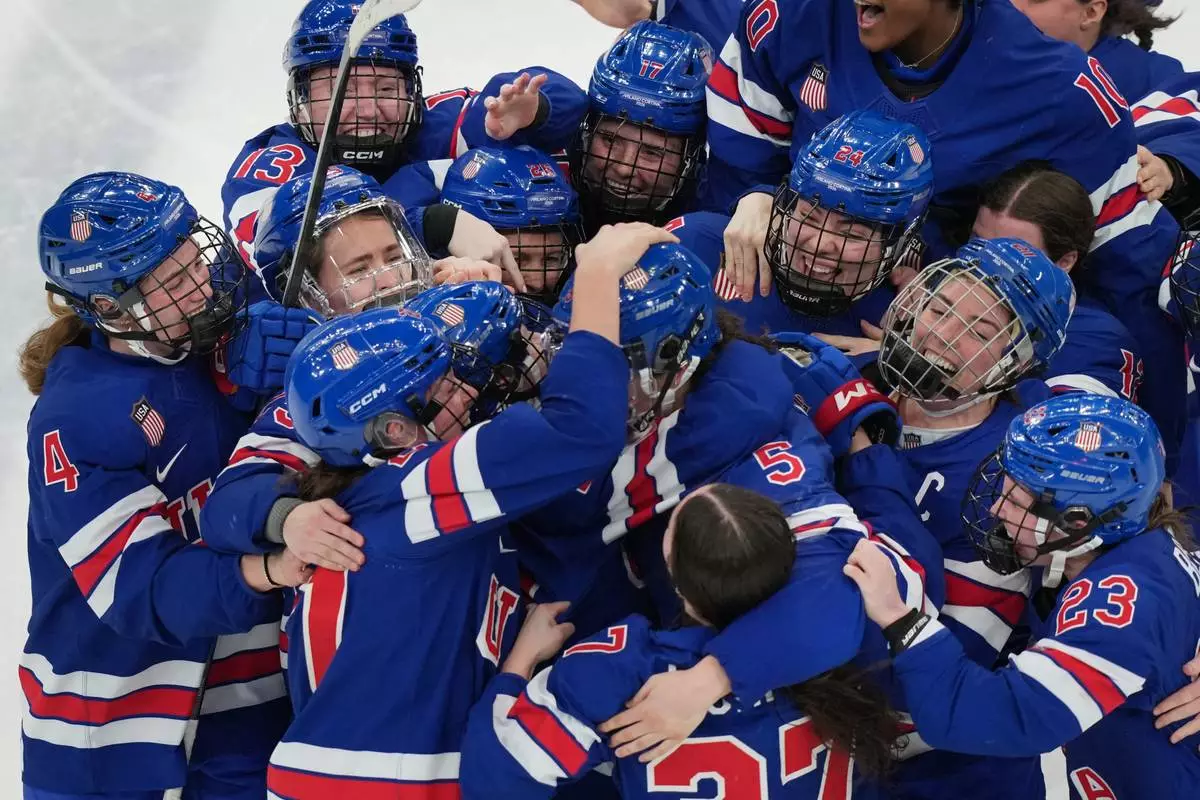 United States players surround Megan Keller (5) after she scored the winning goal in overtime to beat Canada in the women's ice hockey gold medal game at the 2026 Winter Olympics, in Milan, Italy, Thursday, Feb. 19, 2026. (AP Photo/Carolyn Kaster)