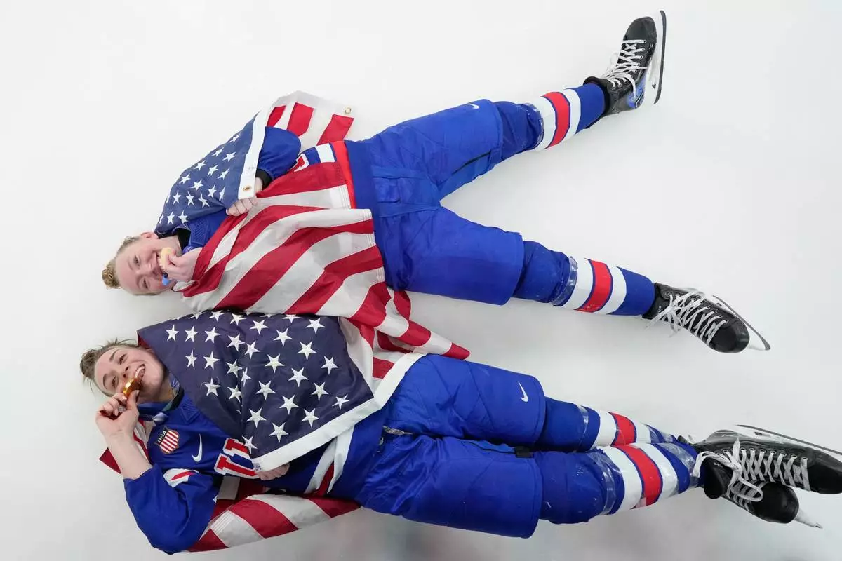 United States' Grace Zumwinkle, right, and Taylor Heise celebrate after victory ceremony for women's ice hockey at the 2026 Winter Olympics, in Milan, Italy, Thursday, Feb. 19, 2026. (AP Photo/Hassan Ammar)