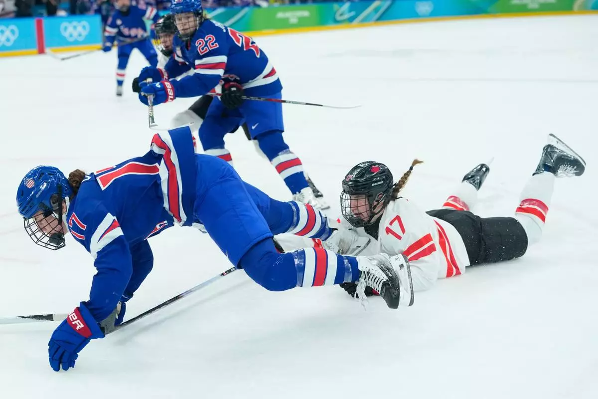 Canada's Ella Shelton (17) trips United States' Britta Curl (17) during a women's ice hockey gold medal game between the United States and Canada at the 2026 Winter Olympics, in Milan, Italy, Thursday, Feb. 19, 2026. (AP Photo/Petr David Josek)