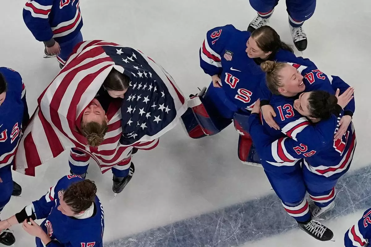 Team United States players celebrate after beating Canada 2-1 in overtime in the women's ice hockey gold medal game at the 2026 Winter Olympics, in Milan, Italy, Thursday, Feb. 19, 2026. (AP Photo/David J. Phillip)
