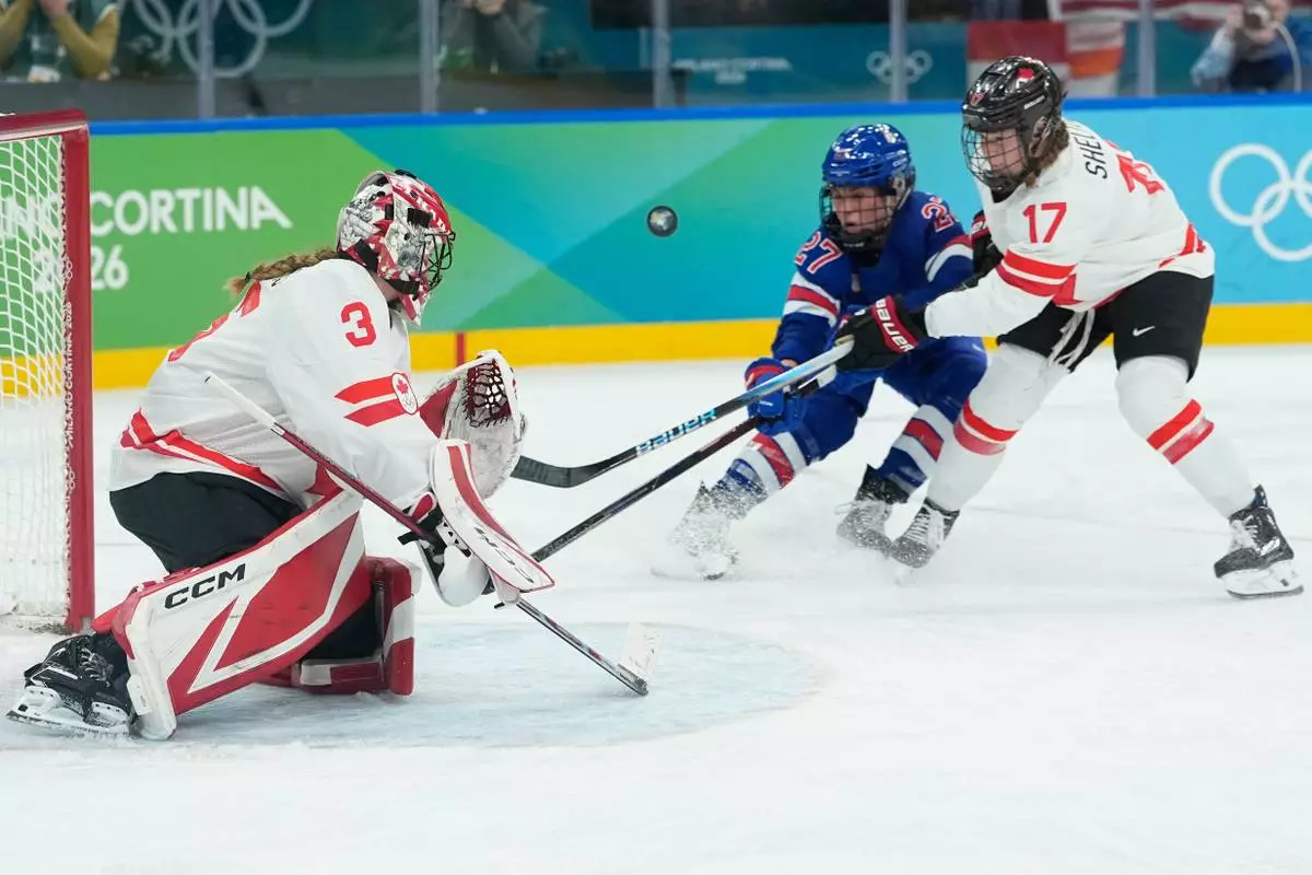 United States' Taylor Heise (27) and Canada's Ella Shelton (17) challenge for the puck during a women's ice hockey gold medal game between the United States and Canada at the 2026 Winter Olympics, in Milan, Italy, Thursday, Feb. 19, 2026. (AP Photo/Petr David Josek)