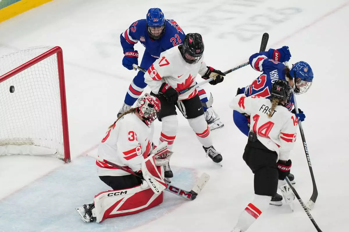 United States' Hilary Knight (21) deflects the puck past Canada goalkeeper Ann-Renee Desbiens (35) for a goal during the third period of the women's ice hockey gold medal game at the 2026 Winter Olympics, in Milan, Italy, Thursday, Feb. 19, 2026. (AP Photo/Carolyn Kaster)