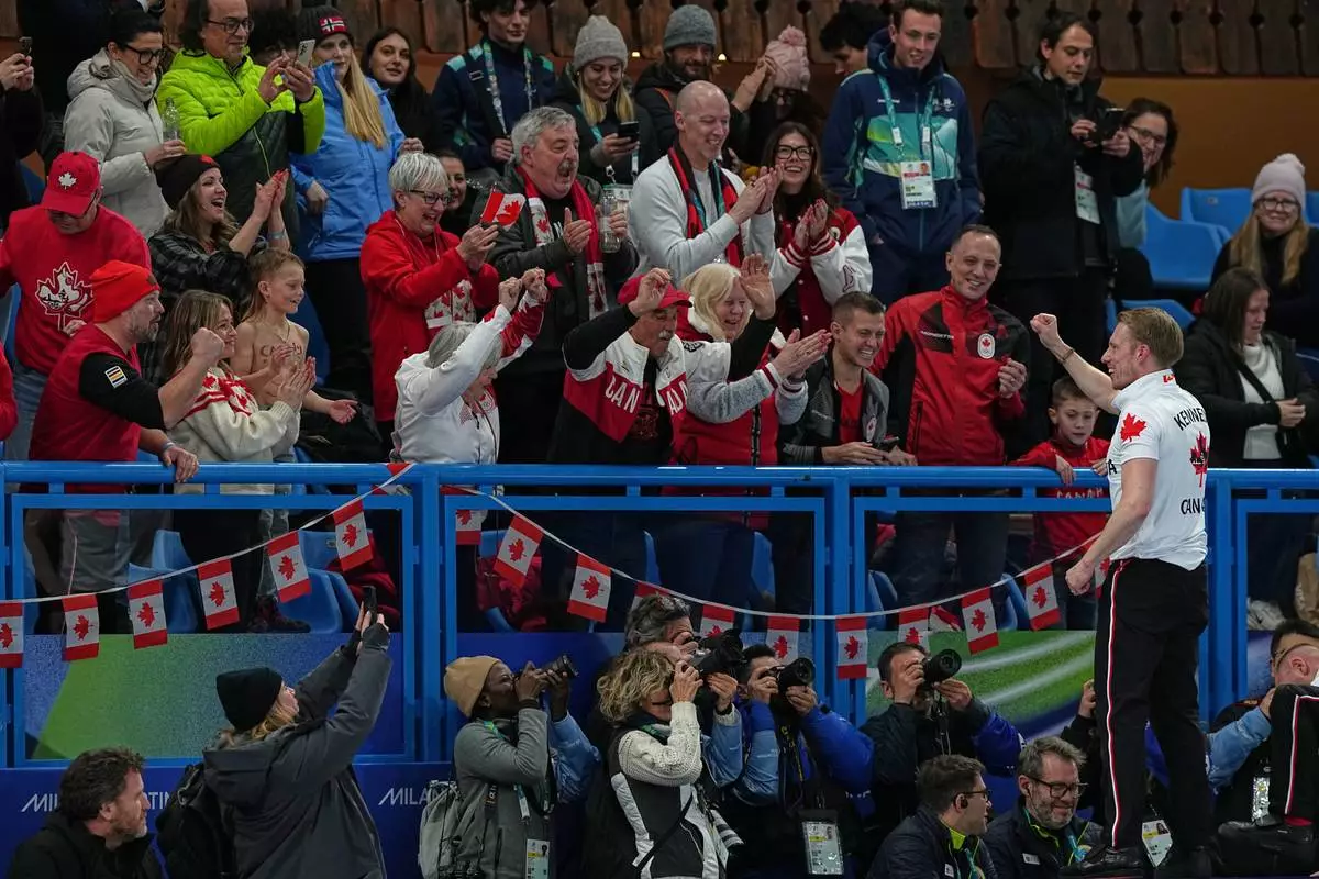 Canada's Marc Kennedy celebrates with fans after defeating Britain in a men's curling gold medal match, at the 2026 Winter Olympics, in Cortina d'Ampezzo, Italy, Saturday, Feb. 21, 2026. (AP Photo/Fatima Shbair)