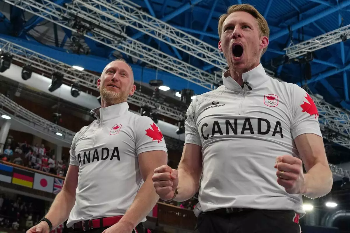 Canada's Brad Jacobs, left, and Marc Kennedy celebrate defeating Britain in a men's curling gold medal match, at the 2026 Winter Olympics, in Cortina d'Ampezzo, Italy, Saturday, Feb. 21, 2026. (AP Photo/Misper Apawu)