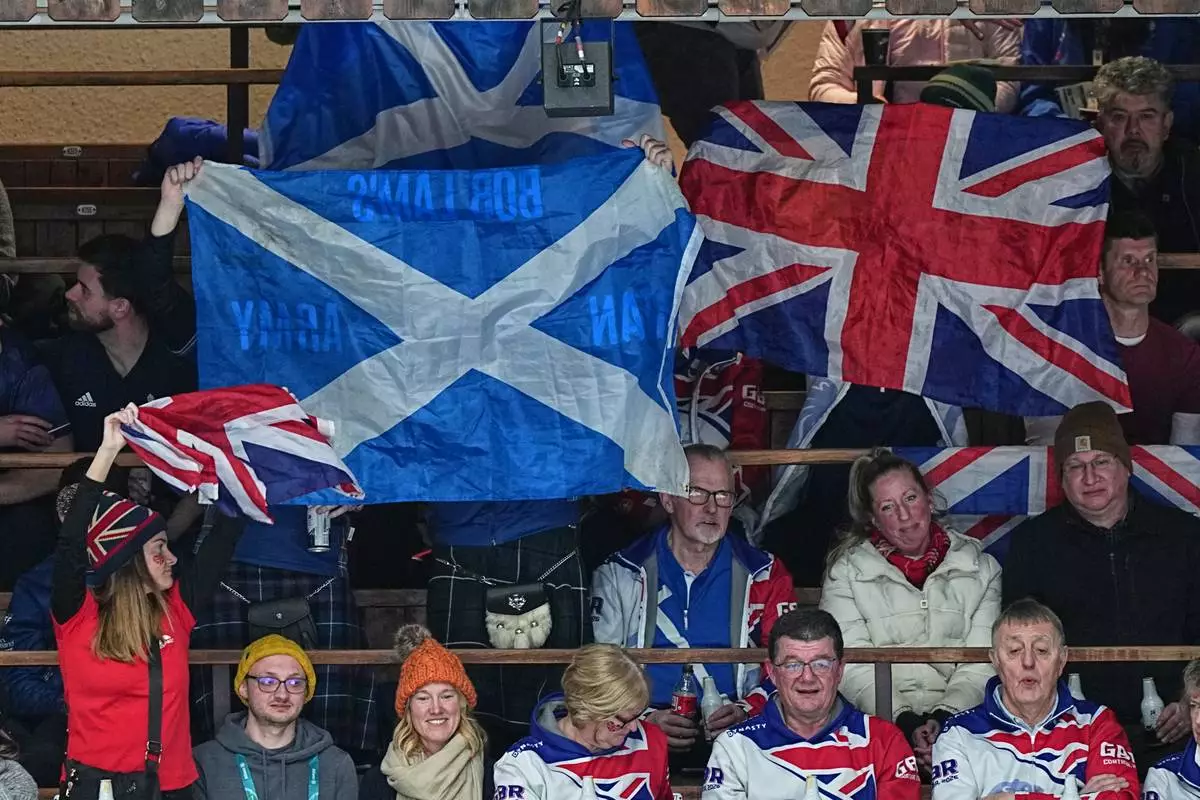 Britain's fans wave flags during a men's curling gold medal match between Britain and Canada, at the 2026 Winter Olympics, in Cortina d'Ampezzo, Italy, Saturday, Feb. 21, 2026. (AP Photo/Fatima Shbair)