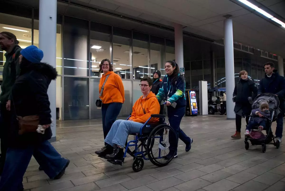A 2026 Winter Olympics volunteer pushes a spectator in a wheelchair, at the venue that hosts the women’s ice hockey, in Milan, Italy, Monday, Feb. 9, 2026. (AP Photo/Vasilisa Stepanenko)
