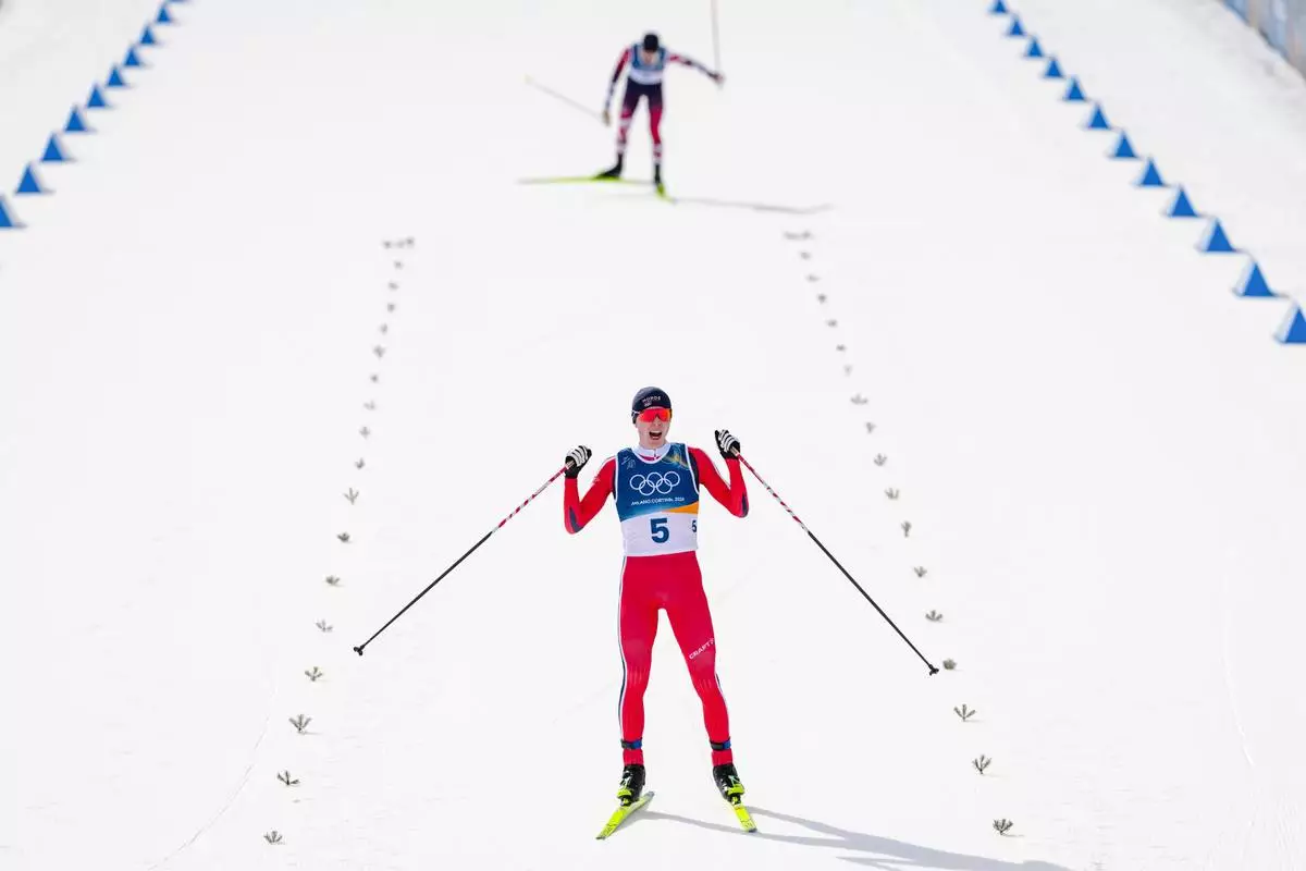 Jens Luraas Oftebro, of Norway, crosses the finish line, ahead of Johannes Lamparter, of Austria, to win the gold medal in the nordic combined individual Gundersen large hill/10km at the 2026 Winter Olympics, in Tesero, Italy, Tuesday, Feb. 17, 2026. (AP Photo/Kirsty Wigglesworth)