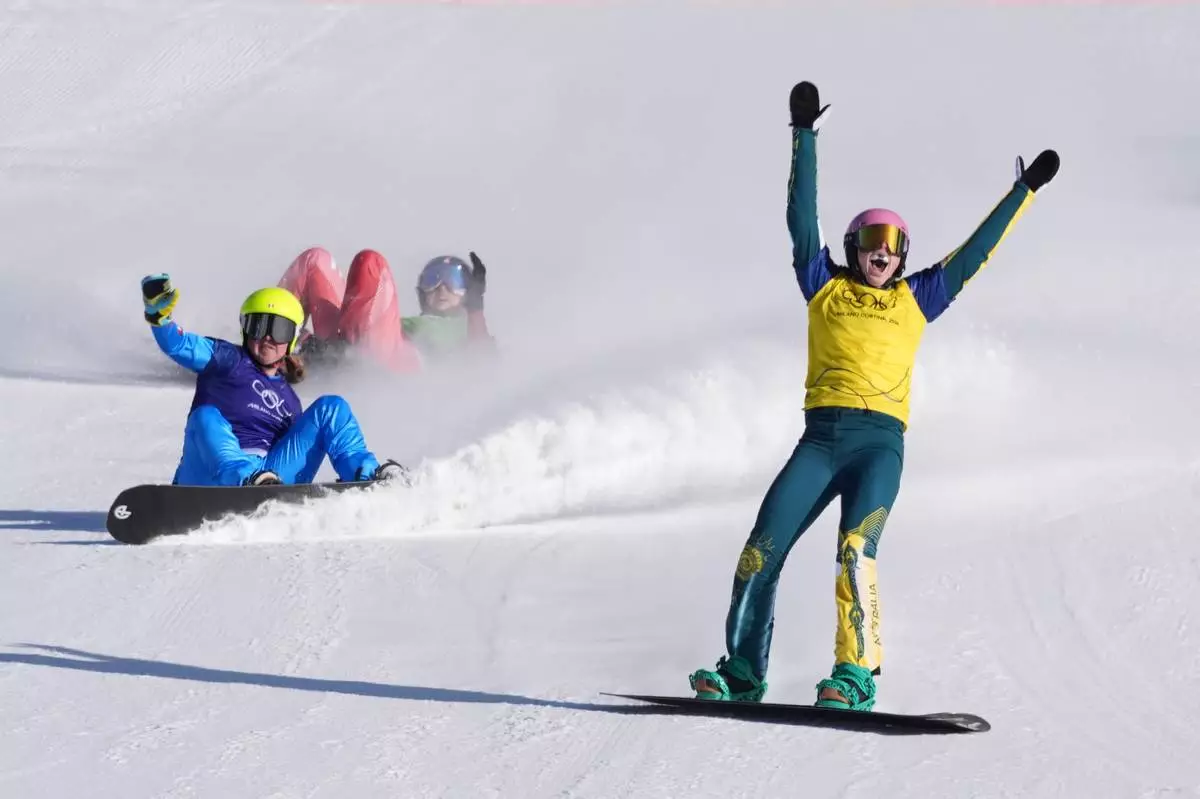 Australia's Josie Baff (17) celebrates her gold medal win past bronze medalist Italy's Michela Moioli (6) and Switzerland's Noemie Wiedmer (3) during the women's snowboard cross finals at the 2026 Winter Olympics, in Livigno, Italy, Friday, Feb. 13, 2026. (AP Photo/Lindsey Wasson)