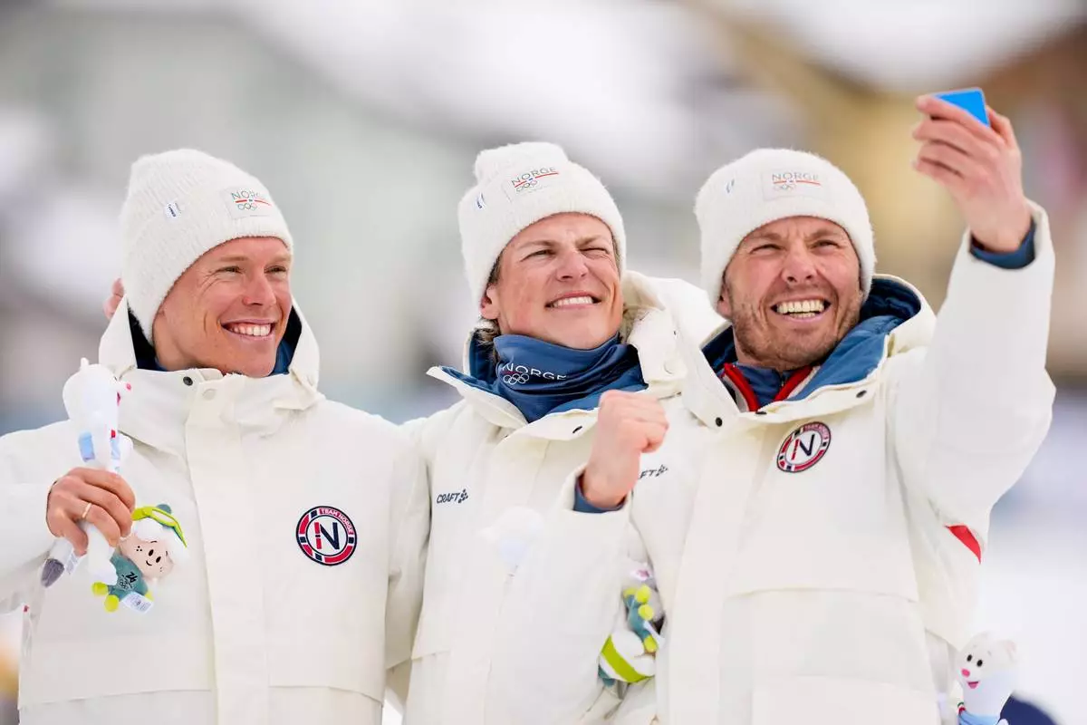 Silver medalist Martin Loewstroem Nyenget, gold medalist Johannes Hoesflot Klaebo and bronze medalist Emil Iversen, all three of Norway, pose on the podium of the cross country skiing men's 50km mass start Classic at the 2026 Winter Olympics, in Tesero, Italy, Saturday, Feb. 21, 2026. (AP Photo/Matthias Schrader)