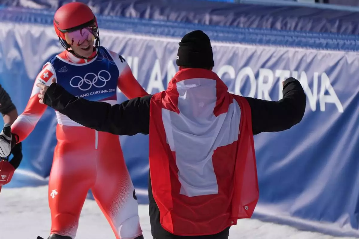 Switzerland's Franjo von Allmen, right, goes to hug his teammate Switzerland's Nef Tanguy at the finish area of an alpine ski men's slalom portion of a team combined race, at the 2026 Winter Olympics, in Bormio, Italy, Monday, Feb. 9, 2026. (AP Photo/Rebecca Blackwell)