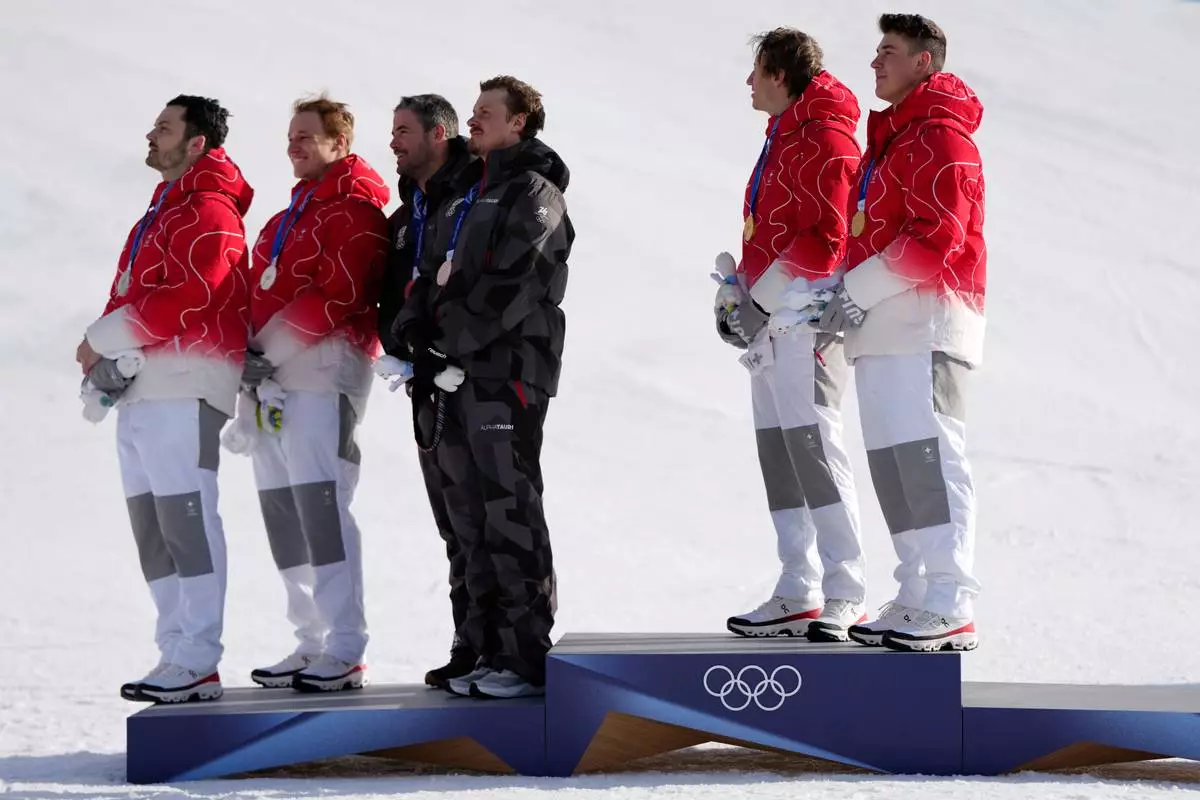 From right, gold medalists Switzerland's Franjo von Allmen, and teammate Tanguy Nef, joint-silver medalists Austria's Manuel Feller and teammate Vincent Kriechmayr, and Switzerland's Marco Odermatt, and teammate Loic Meillard, listen to the Swiss national anthem at the finish area of an alpine ski men's team combined race, at the 2026 Winter Olympics, in Bormio, Italy, Monday, Feb. 9, 2026. (AP Photo/Julia Demaree Nikhinson)