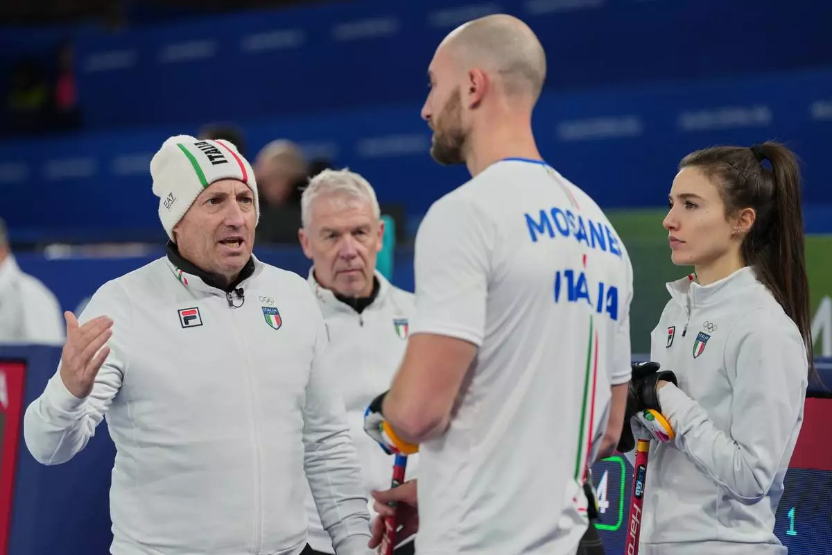 Italy's national coach Marco Mariani, left, speaks to his athletes, Stefania Constantini, and Amos Mosaner during the mixed doubles round robin phase of the curling competition against Canada at the 2026 Winter Olympics, in Cortina d'Ampezzo, Italy, Thursday, Feb. 5, 2026. (AP Photo/Misper Apawu)