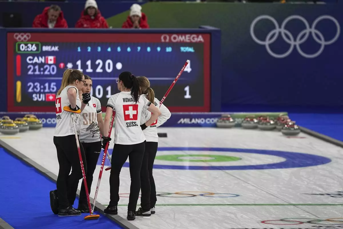 Switzerland's Silvana Tirinzoni, Alina Paetz, Selina Witschonke, and Carole Howald strategize during the women's curling round robin session against Canada at the 2026 Winter Olympics, in Cortina d'Ampezzo, Italy, Saturday, Feb. 14, 2026. (AP Photo/Fatima Shbair)