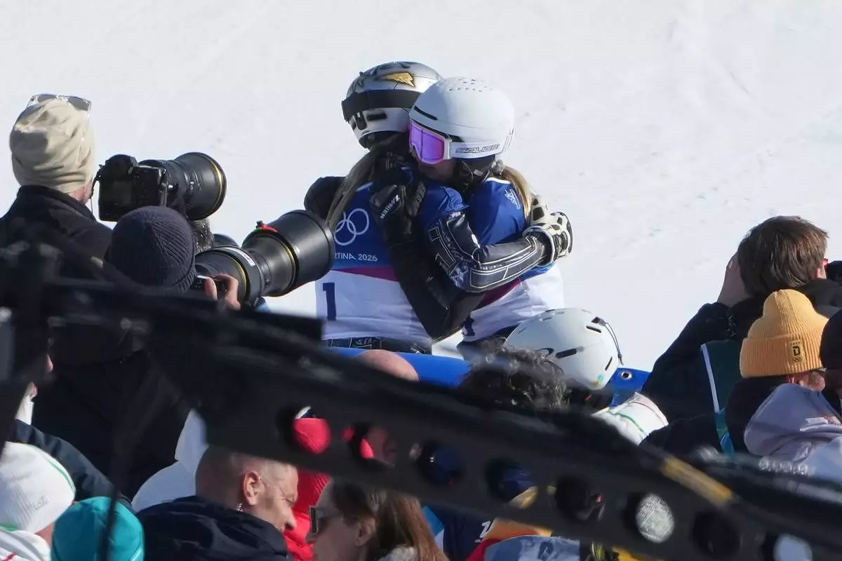 Czechia's Ester Ledecka, left, and Austria's Sabine Payer hug after Payer advanced during the women's snowboarding parallel giant slalom finals at the 2026 Winter Olympics, in Livigno, Italy, Sunday, Feb. 8, 2026. (AP Photo/Lindsey Wasson)