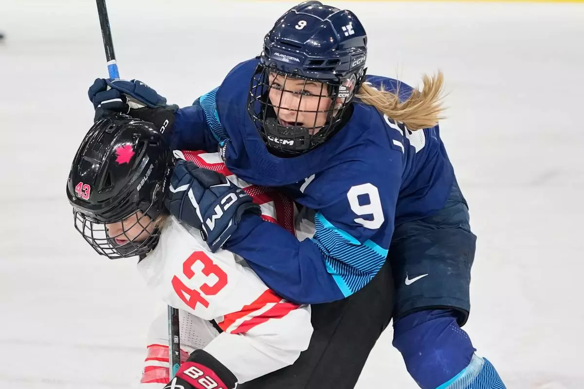 Finland's Nelli Laitinen, right, challenges Canada's Kristin O'Neill during a preliminary round match of women's ice hockey between Finland and Canada at the 2026 Winter Olympics, in Milan, Italy, Thursday, Feb. 12, 2026. (AP Photo/Hassan Ammar)