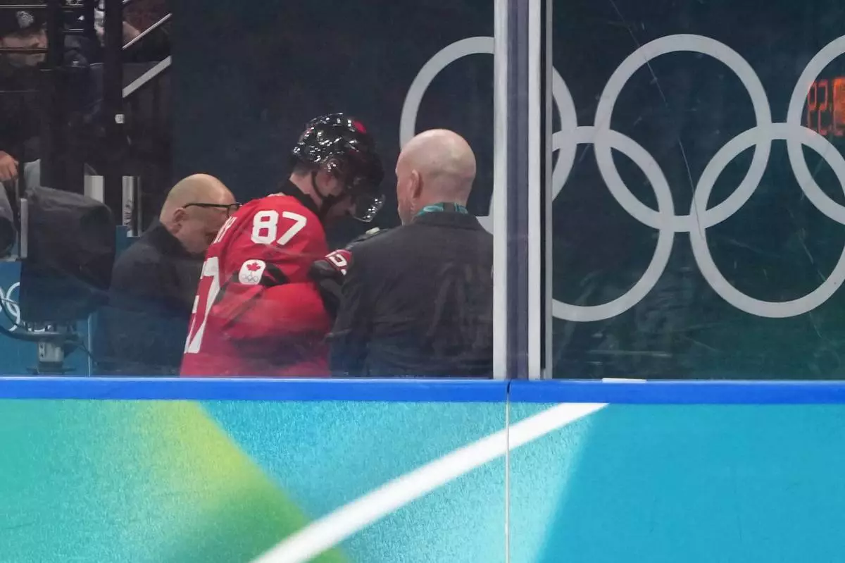 Canada's Sidney Crosby (87) is helped as he leaves the bench after being checked against the boards during the second period of a men's ice hockey quarterfinal game between Canada and Czechia at the 2026 Winter Olympics, in Milan, Italy, Wednesday, Feb. 18, 2026. (AP Photo/Carolyn Kaster)