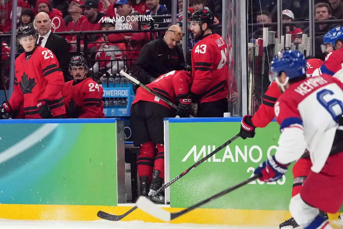 Canada's Sidney Crosby is helped as he leaves the bench after being checked against the boards during the second period of a men's ice hockey quarterfinal game between Canada and Czechia at the 2026 Winter Olympics, in Milan, Italy, Wednesday, Feb. 18, 2026. (AP Photo/Carolyn Kaster)