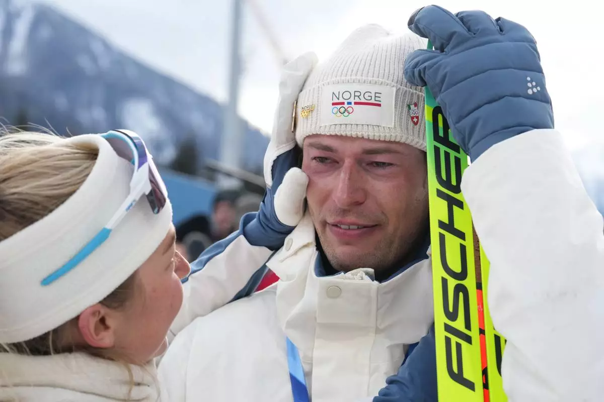 ADDS NAME OF TEAMMATE - Sturla Holm Laegreid, of Norway, reacts after he won bronze as teammate Ingrid Landmark Tandrevold comforts him after the men's 20-kilometer individual biathlon race at the 2026 Winter Olympics in Anterselva, Italy, Tuesday, Feb. 10, 2026. (AP Photo/Andrew Medichini)