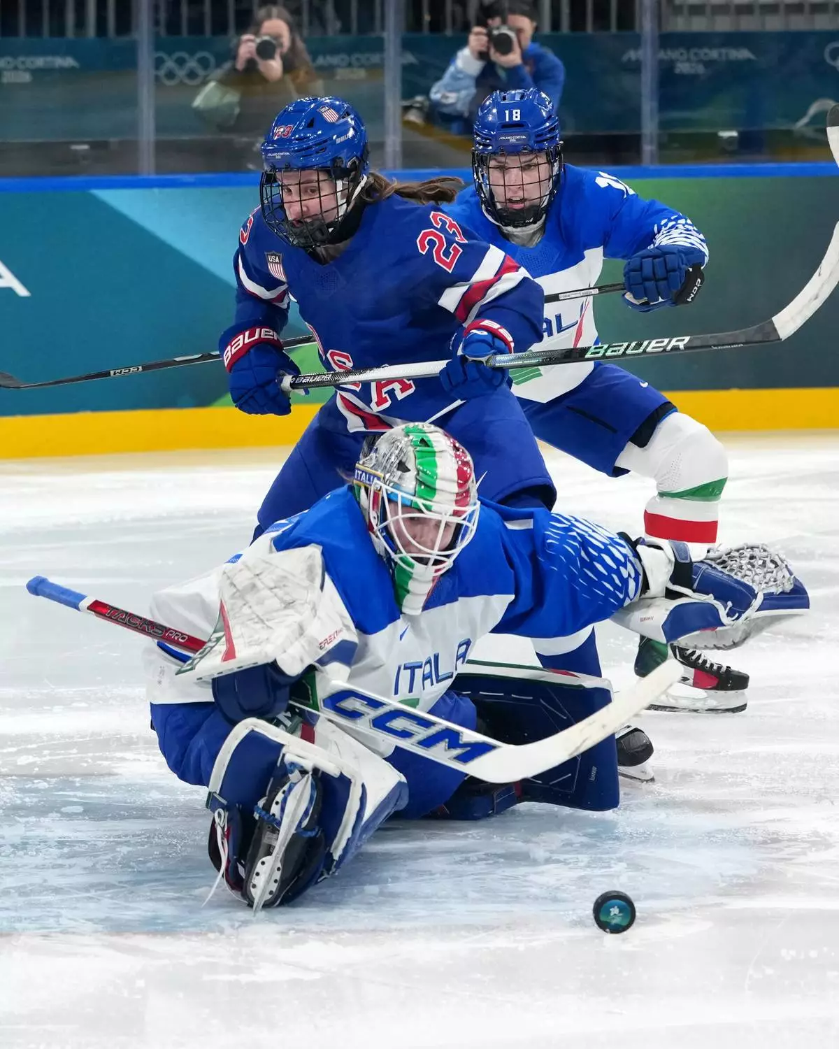 Italy's goalkeeper Gabriella Durante reaches for the puck as United States' Hannah Bilka (23) and Italy's Franziska Stocker (18) close in during the second period of a women's ice hockey quarterfinal match at the 2026 Winter Olympics, in Milan, Italy, Friday, Feb. 13, 2026. (AP Photo/Carolyn Kaster)