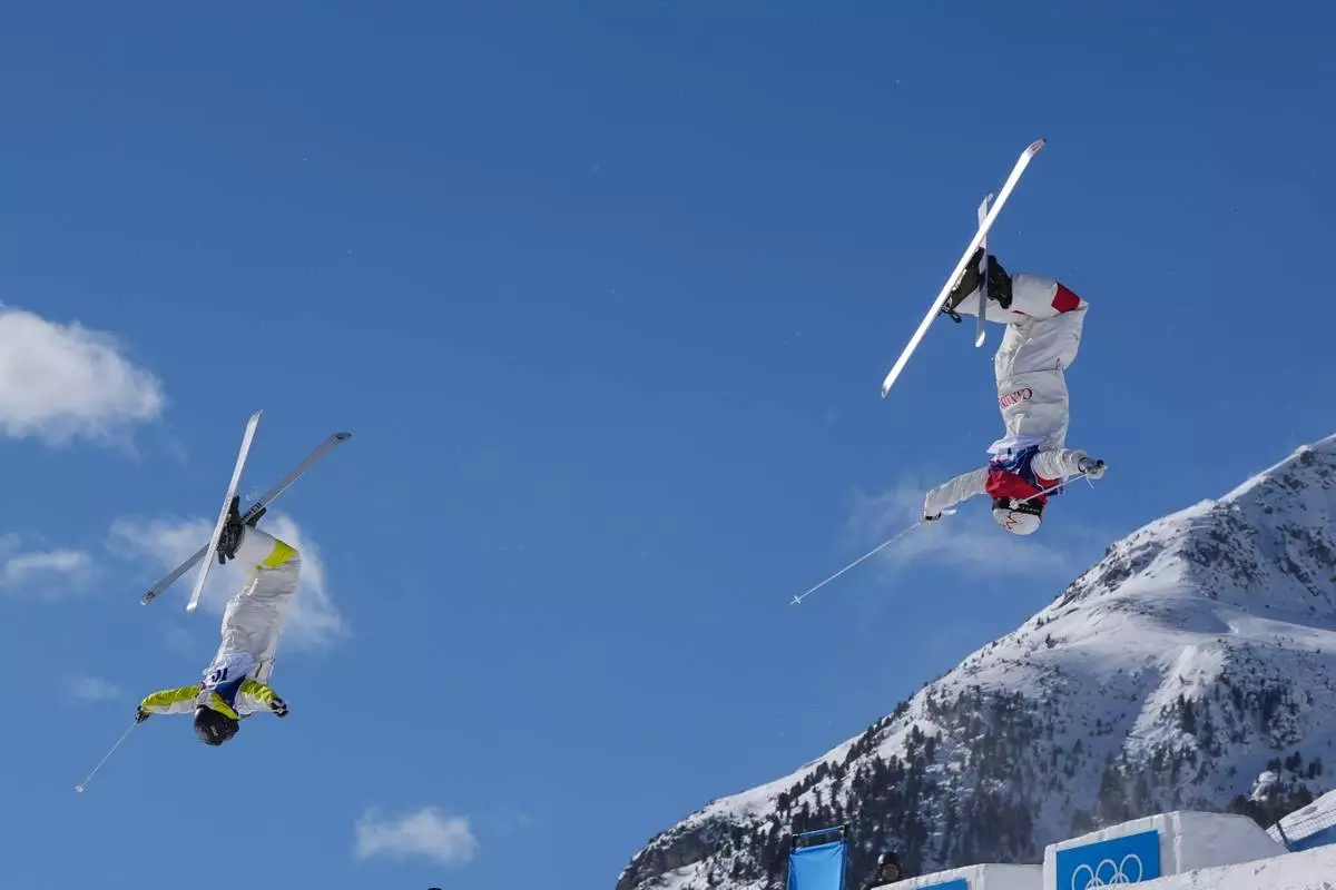 Canada's Mikael Kingsbury (4), right, and Kazakhstan's Pavel Kolmakov (10) compete during the men's freestyle skiing dual moguls finals at the 2026 Winter Olympics, in Livigno, Italy, Sunday, Feb. 15, 2026. (AP Photo/Gregory Bull)