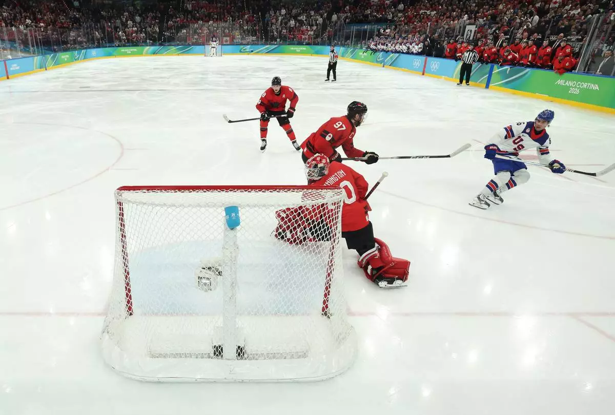 United States' Jack Hughes (86) scores the game-winning goal against Canada's Connor McDavid (97) and Jordan Binnington (50) in overtime during a men's ice hockey gold medal game between Canada and the United States at the 2026 Winter Olympics, in Milan, Italy, Sunday, Feb. 22, 2026. (Bruce Bennett/Pool Photo via AP)