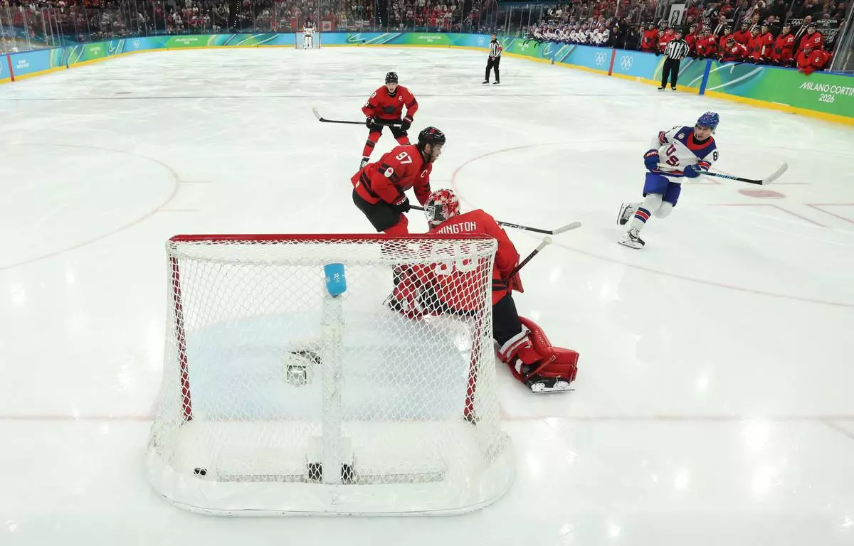 United States' Jack Hughes (86) scores the game winning goal against Canada's Connor McDavid (97) and Jordan Binnington (50) in overtime during a men's ice hockey gold medal game between Canada and the United States at the 2026 Winter Olympics, in Milan, Italy, Sunday, Feb. 22, 2026. (Bruce Bennett/Pool Photo via AP)
