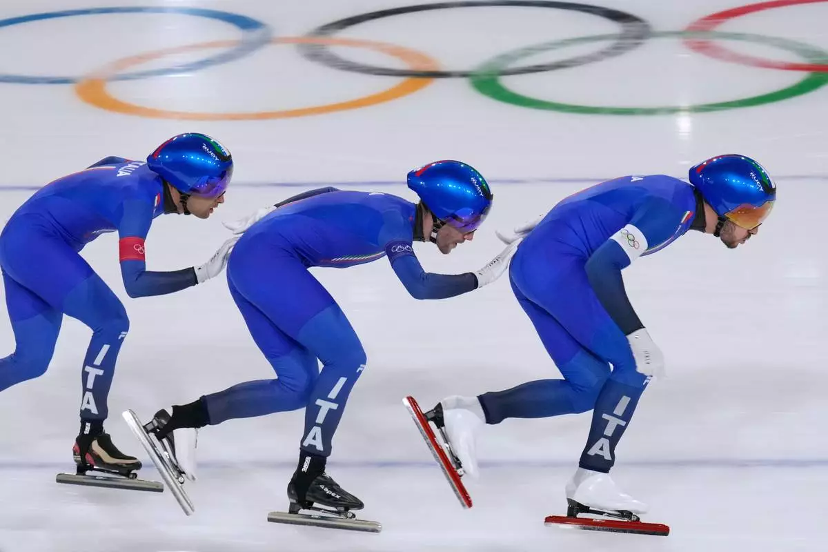 Team Italy with Davide Ghiotto, white armband, Andrea Giovannini, red armband, and Michele Malfatti, blue armband, compete to win the gold medal in the final of the men's team pursuit speedskating race at the 2026 Winter Olympics, in Milan, Italy, Tuesday, Feb. 17, 2026. (AP Photo/Luca Bruno)