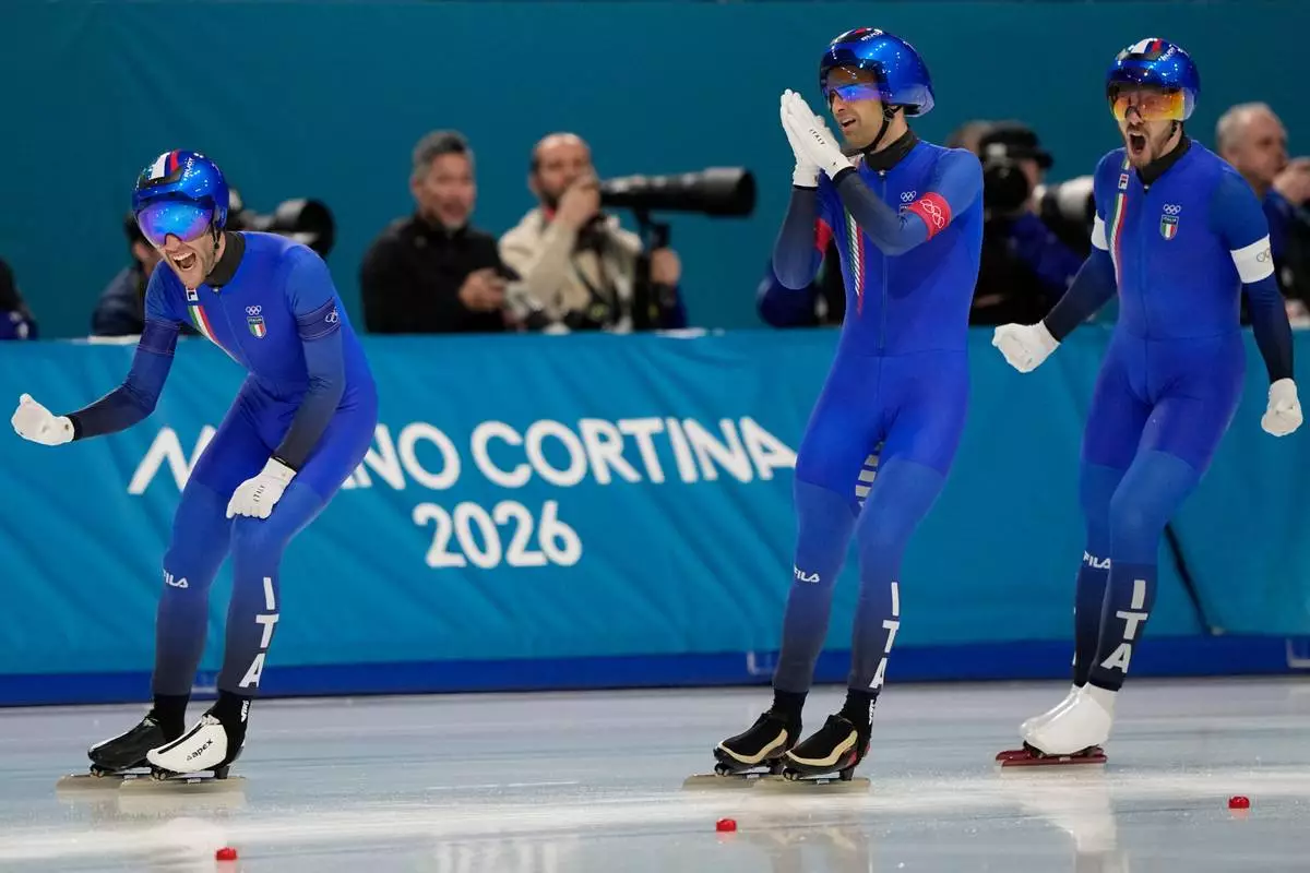 Team Italy with Michele Malfatti, left, Andrea Giovannini, center, and Davide Ghiotto, right, celebrate winning the gold medal in the final of the men's team pursuit speedskating race at the 2026 Winter Olympics, in Milan, Italy, Tuesday, Feb. 17, 2026. (AP Photo/Ben Curtis)