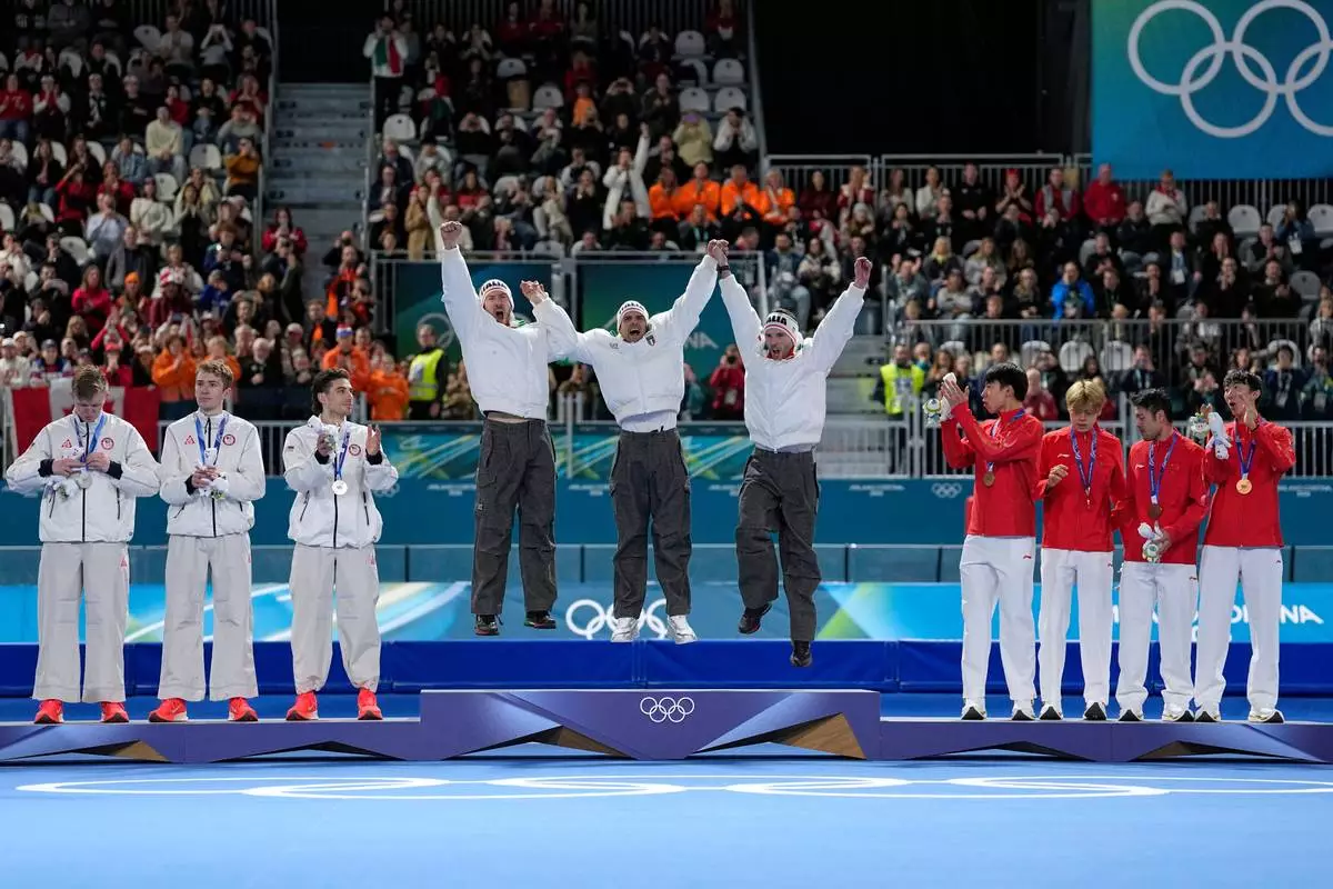 Team Italy, center and goal medal, team USA, left and silver medal, and team China celebrate on the podium of the men's team pursuit speedskating race at the 2026 Winter Olympics, in Milan, Italy, Tuesday, Feb. 17, 2026. (AP Photo/Ben Curtis)