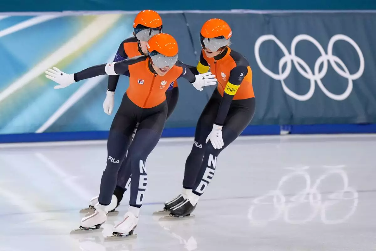 Team Netherlands with Joy Beune, white armband, Marijjke Groenewoud, yellow armband, and Antoinette Rijpma-de Jong, blue armband, celebrates after winning the semifinal of the women's team pursuit speedskating race at the 2026 Winter Olympics, in Milan, Italy, Tuesday, Feb. 17, 2026. (AP Photo/Luca Bruno)
