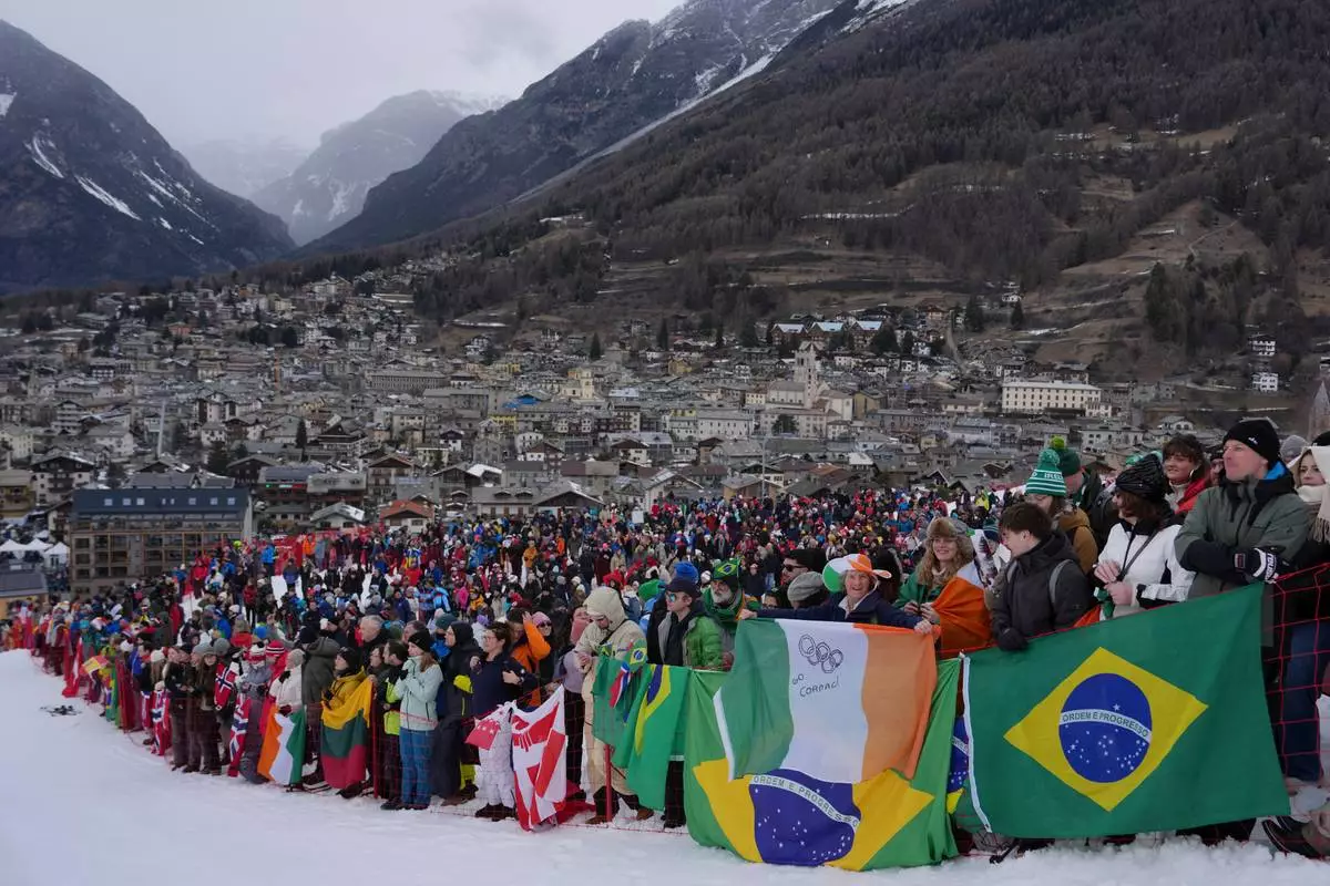Spectators hold flags, including the Brazilian flag, right, as they watch an alpine ski, men's giant slalom race, at the 2026 Winter Olympics, in Bormio, Italy, Saturday, Feb. 14, 2026. (AP Photo/Julia Demaree Nikhinson)