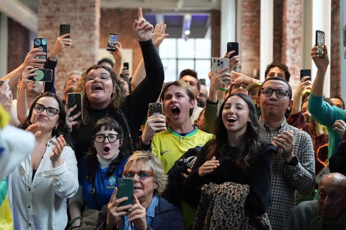 Supporters of Brazil's Lucas Pinheiro Braathen react at the Brazil House as he starts his second run in the men's giant slalom at the 2026 Winter Olympics, in Milan, Italy, Saturday, Feb. 14, 2026. (AP Photo/Antonio Calanni)