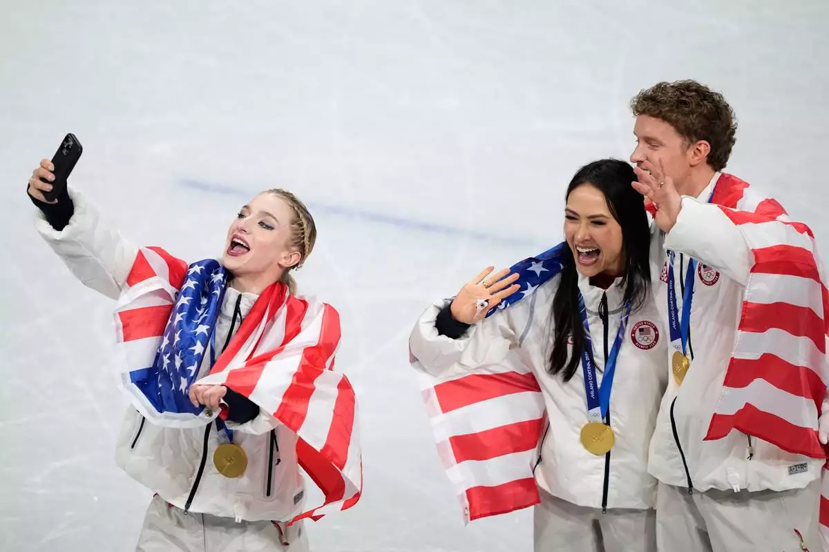 From left, Amber Glenn and ice dance team Madison Chock and Evan Bates celebrate winning the gold medal after the figure skating team event at the 2026 Winter Olympics, in Milan, Italy, Sunday, Feb. 8, 2026. (AP Photo/Natacha Pisarenko)