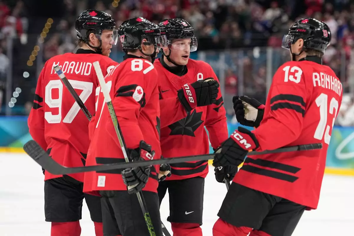 Canada's Cale Makar (8) celebrates with teammates Canada's Connor McDavid (97), Canada's Sidney Crosby (87), Canada's Sam Reinhart (13) after scoring during a preliminary round game of men's ice hockey between Canada and France at the 2026 Winter Olympics, in Milan, Italy, Sunday, Feb. 15, 2026. (AP Photo/Hassan Ammar)