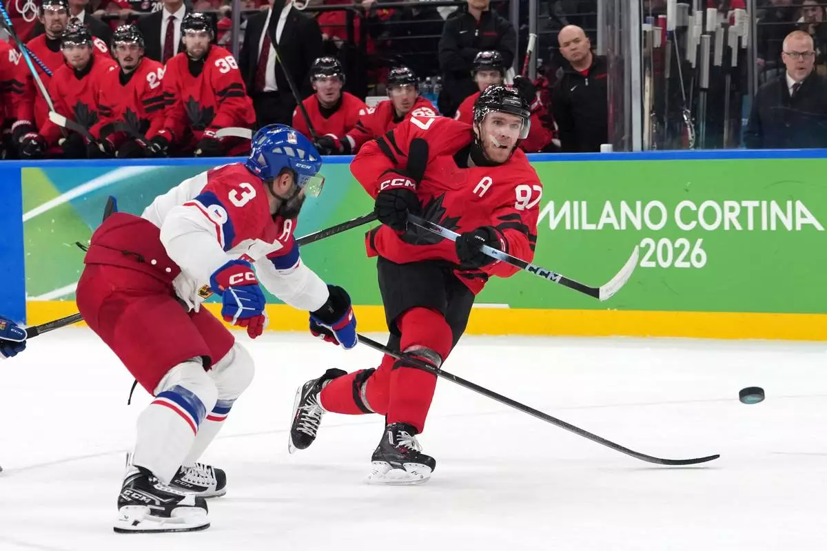 Canada's Connor McDavid (97) takes a shot as he is defended by Czechia's Radko Gudas (3) during the second period of a men's ice hockey quarterfinal game at the 2026 Winter Olympics, in Milan, Italy, Wednesday, Feb. 18, 2026. (AP Photo/Carolyn Kaster)