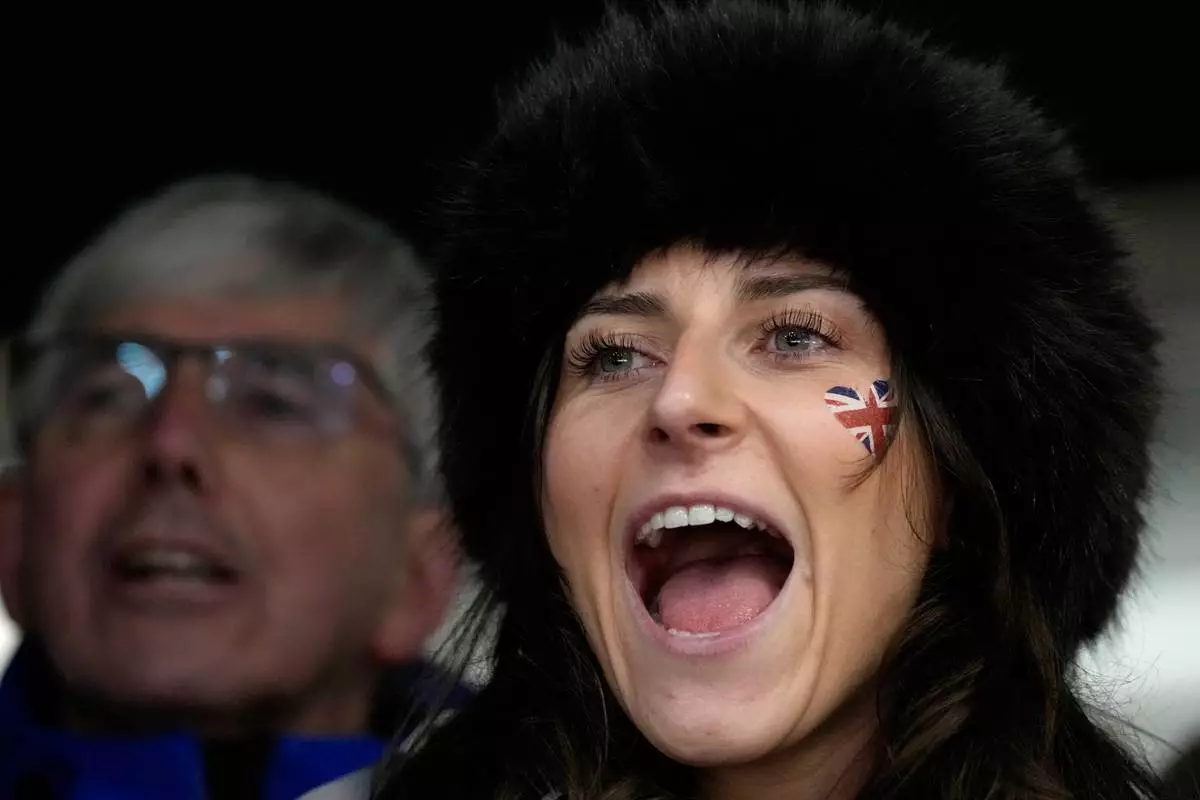 A person cheers during a women's skeleton run at the 2026 Winter Olympics, in Cortina d'Ampezzo, Italy, Friday, Feb. 13, 2026. (AP Photo/Alessandra Tarantino)