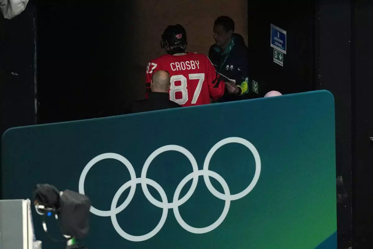 Canada's Sidney Crosby (87) is led away from the ice after being injured during the second period of a men's ice hockey quarterfinal game between Canada and Czechia at the 2026 Winter Olympics, in Milan, Italy, Wednesday, Feb. 18, 2026. (AP Photo/Hassan Ammar)