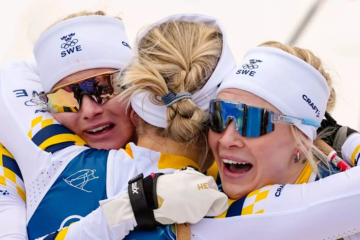 Gold medalist Linn Svahn, of Sweden, center, hugs silver medalist Jonna Sundling, right, and bronze medalist Maja Dahlqvist, both also of Sweden, after the cross-country skiing women's sprint classic at the 2026 Winter Olympics, in Tesero, Italy, Tuesday, Feb. 10, 2026. (AP Photo/Matthias Schrader)