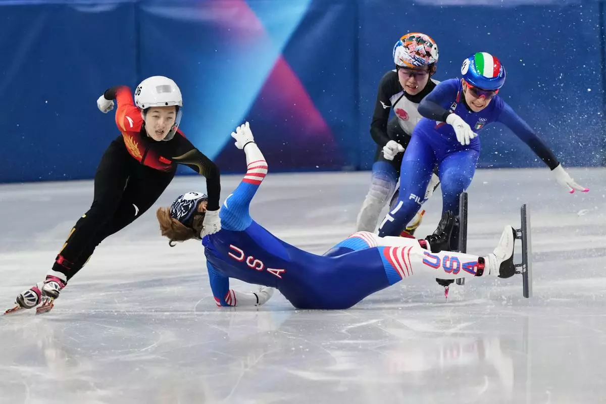 Corinne Stoddard of the United States wipes out as Xinran Wang of the People's Republic of China moves past to win while competing in the women's 500 meter short track speed skating at the 2026 Winter Olympics, in Milan, Italy, Tuesday, Feb. 10, 2026. (AP Photo/Francisco Seco)