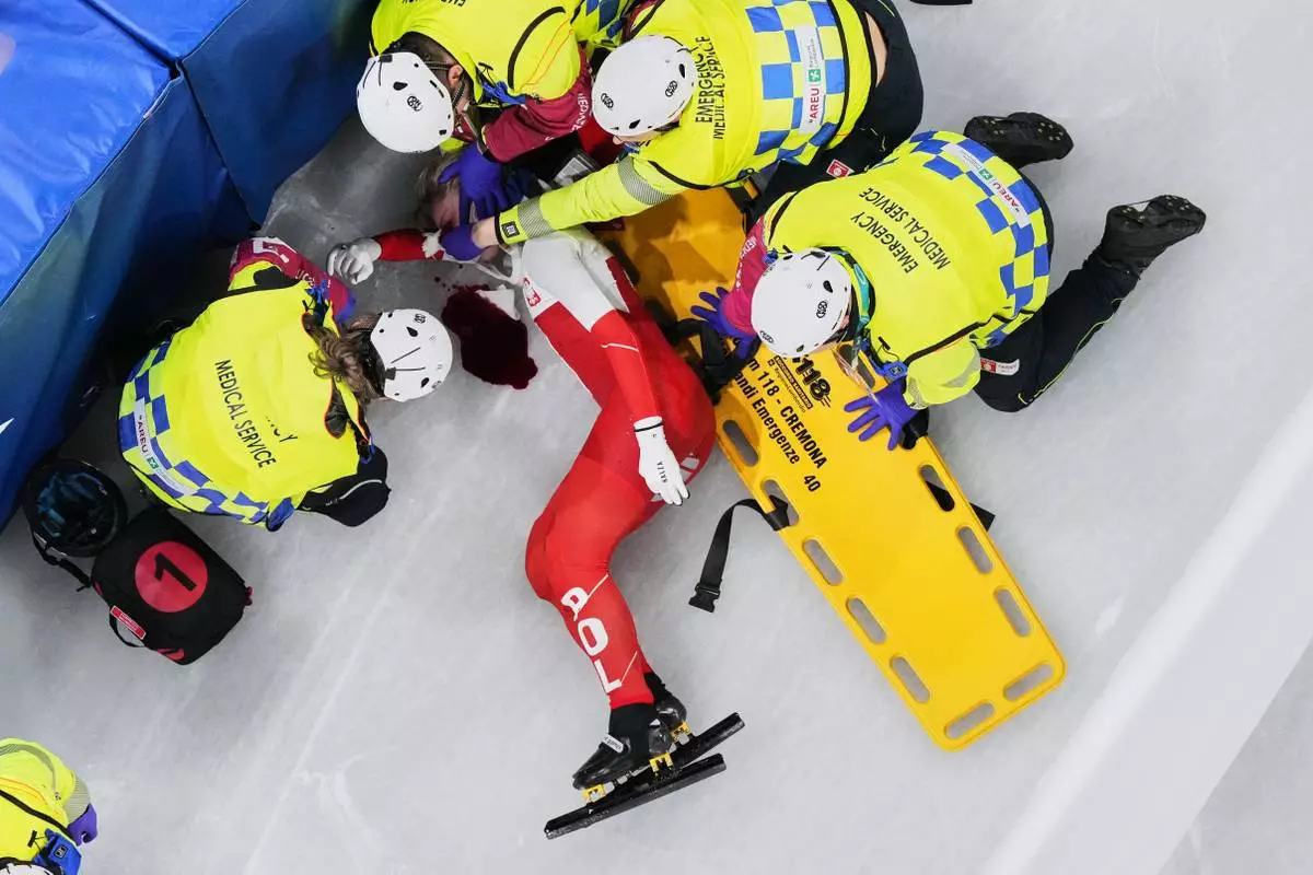 Kamila Sellier of Poland is assisted by the emergency medical service team after an injury due to a fall during a short track speed skating women's 1500 meters quarterfinal at the 2026 Winter Olympics, in Milan, Italy, Friday, Feb. 20, 2026. (AP Photo/Bernat Armangue)