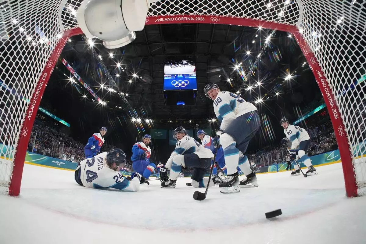 A shot by Slovakia's Adam Ruzicka (21) goes into an open net past Finland's Mikko Rantanen (96), and Finland's Roope, Hintz (24), and Finland's Miro Heiskanen (41) in the third period during a preliminary round match of men's ice hockey at the 2026 Winter Olympics, in Milan, Italy, Wednesday, Feb. 11, 2026. (Mike Segar/Pool Photo via AP)
