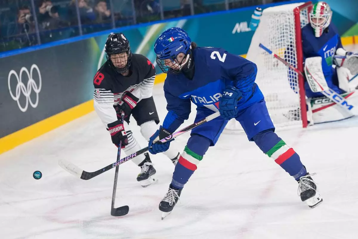 Japan's Suzuka Maeda, left, challenges Italy's Amie Varano during a preliminary round match of women's ice hockey between Japan and Italy at the 2026 Winter Olympics, in Milan, Italy, Monday, Feb. 9, 2026. (AP Photo/Petr David Josek)