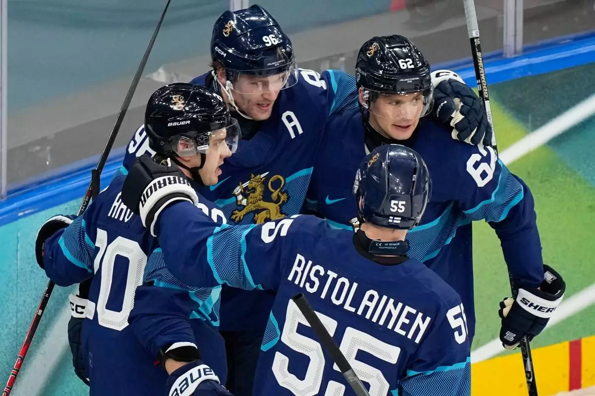Finland's Sebastian Aho, left, celebrates with teammates after scoring his sides first goal during a preliminary round match of men's ice hockey between Finland and Italy at the 2026 Winter Olympics, in Milan, Italy, Saturday, Feb. 14, 2026. (AP Photo/Hassan Ammar)
