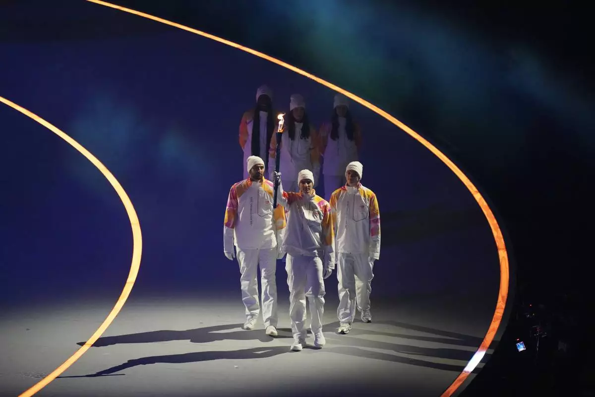 The Olympic torch is carried during the Olympic opening ceremony at the 2026 Winter Olympics, in Milan, Italy, Friday, Feb. 6, 2026. (AP Photo/Stephanie Scarbrough)