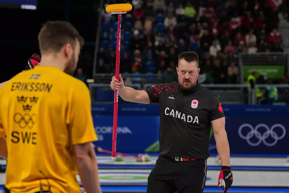 Canada's Ben Hebert, and Sweden's Oskar Eriksson in action during the men's curling round robin session, at the 2026 Winter Olympics, in Cortina d'Ampezzo, Italy, Friday, Feb. 13, 2026. (AP Photo/Misper Apawu)