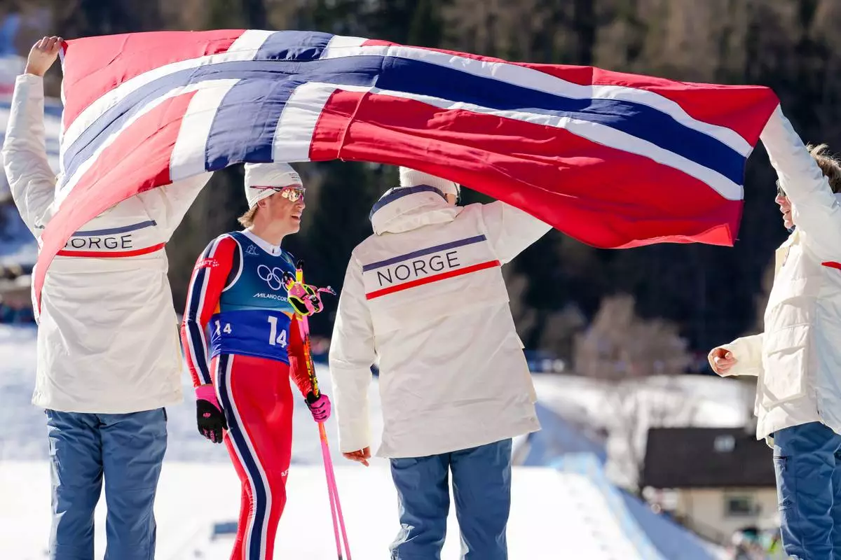Johannes Hoesflot Klaebo, of Norway, 2nd left, joins his teammates after crossing the finish line to win the gold medal in the cross country skiing men's 4 x 7.5km relay at the 2026 Winter Olympics, in Tesero, Italy, Sunday, Feb. 15, 2026. (AP Photo/Kirsty Wigglesworth)
