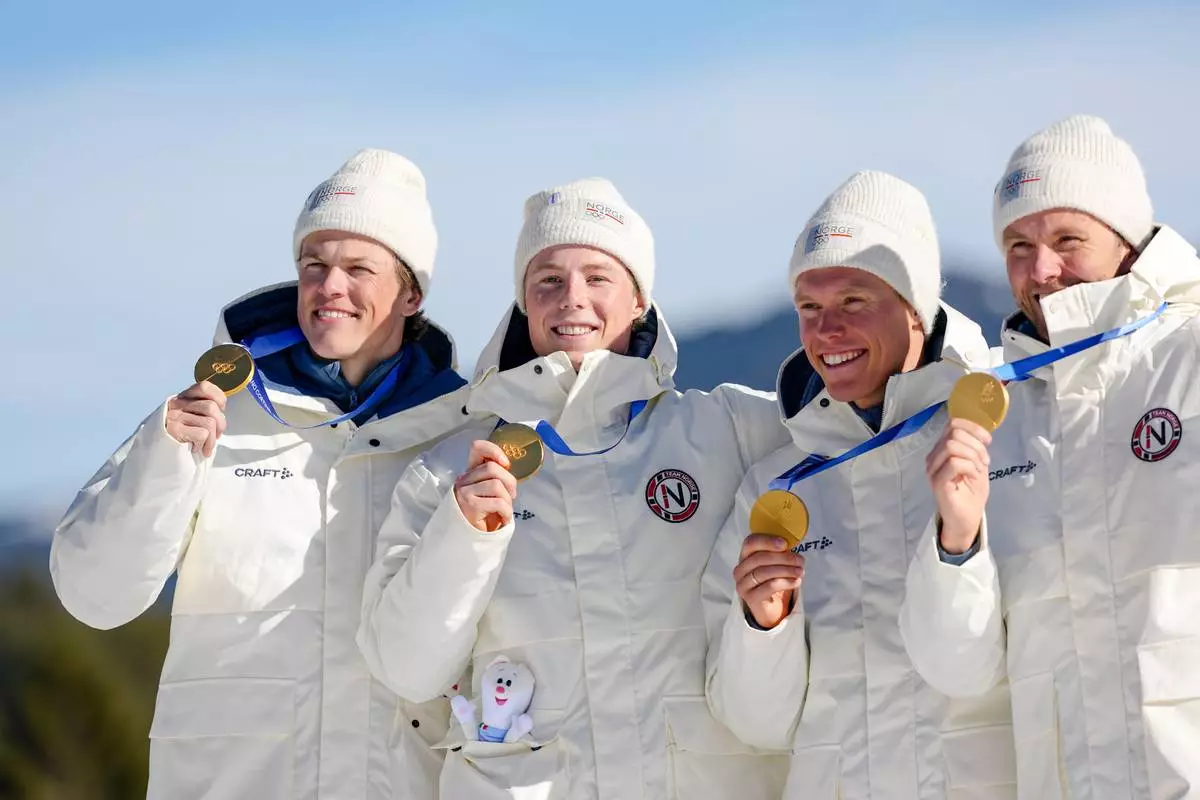 Johannes Hoesflot Klaebo, Einar Hedegart, Martin Loewstroem Nyenget and Emil Iversen, of Norway, pose on the podium after winning the gold medal in the cross country skiing men's 4 x 7.5km relay at the 2026 Winter Olympics, in Tesero, Italy, Sunday, Feb. 15, 2026. (AP Photo/Matthias Schrader)